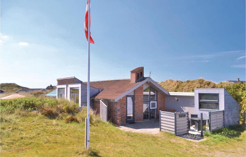 una casa con una bandera delante de ella en Amazing Home In Hvide Sande With 3 Bedrooms, Sauna And Wifi, en Havrvig