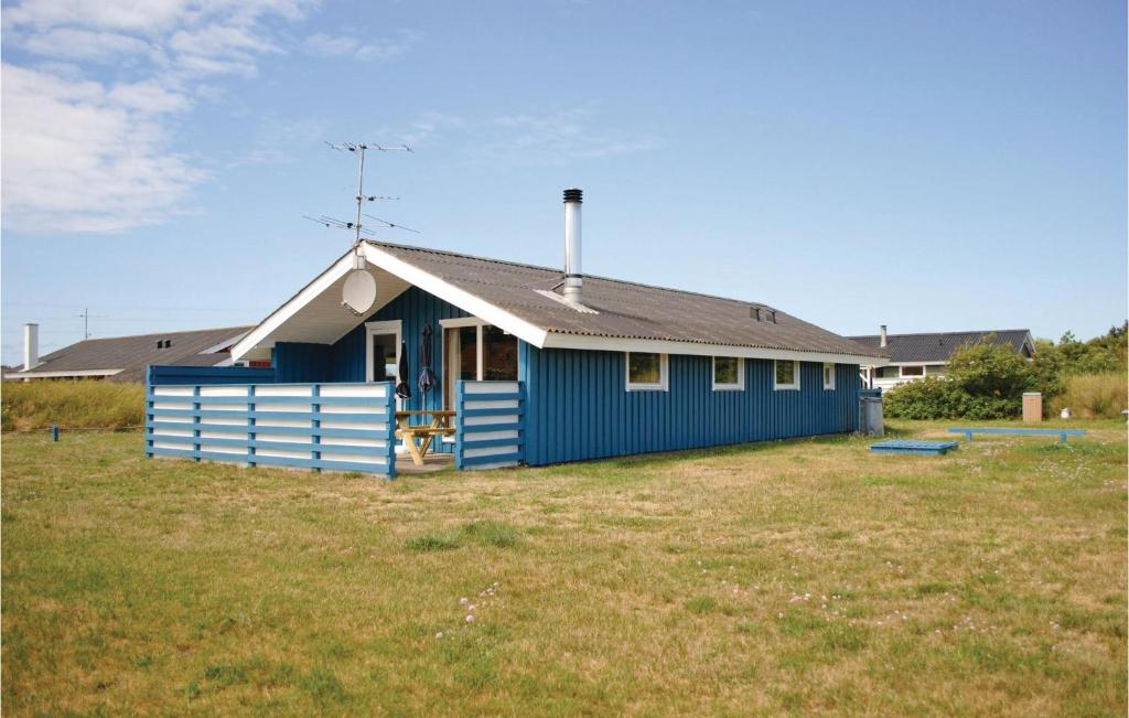 a blue house sitting in a field of grass at Awesome Home In Hvide Sande With 3 Bedrooms And Wifi in Nørre Lyngvig