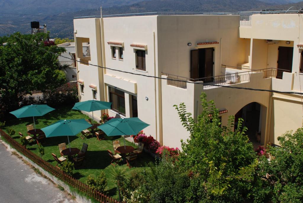 a building with chairs and umbrellas in front of it at Aptera Hotel in Megála Khoráfia