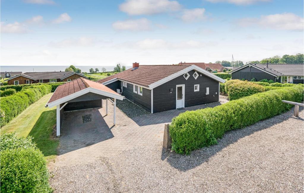 a black house with a roof on a gravel driveway at Awesome Home In Sjlund With 4 Bedrooms, Sauna And Wifi in Hejls