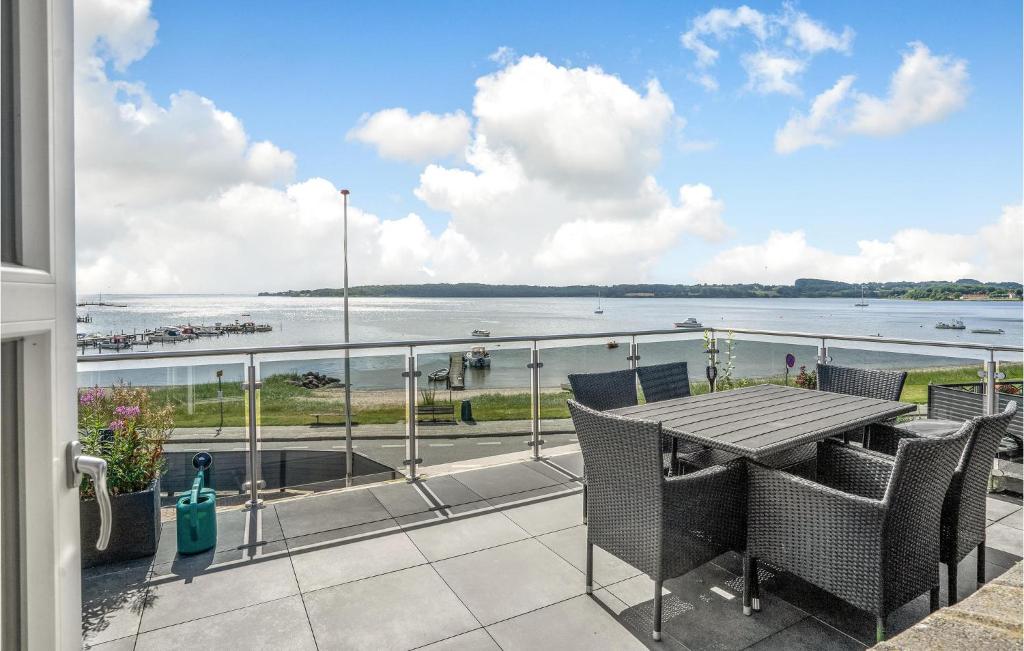balcón con mesa, sillas y vistas al agua en Lovely Home In Rdekro With Kitchen, en Diernæs