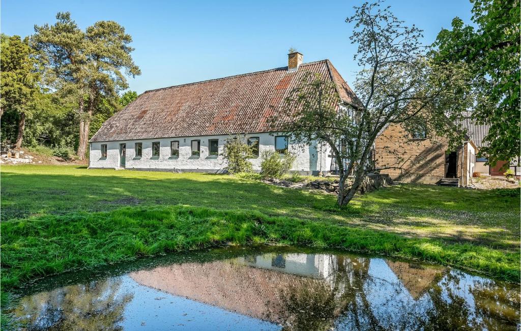 uma casa velha com um lago em frente em Stunning Home In Haarby With Kitchen em Brunshuse