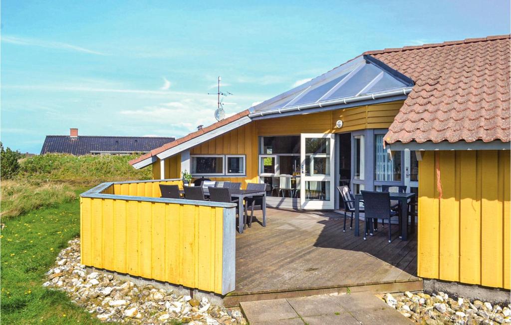 ein gelbes Haus mit einer Terrasse mit Tisch und Stühlen in der Unterkunft Gorgeous Home In Hvide Sande With Sauna in Bjerregård