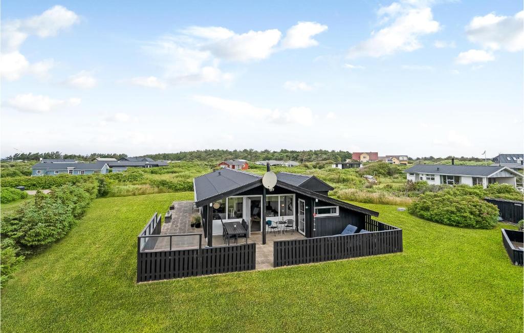 a black tiny house on a green field at Nice Home In Hjrring With Kitchen in Lønstrup