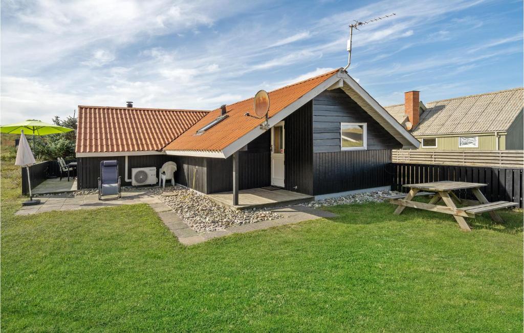 a small black house with a picnic table and a bench at Awesome Home In Hvide Sande With Kitchen in Hvide Sande