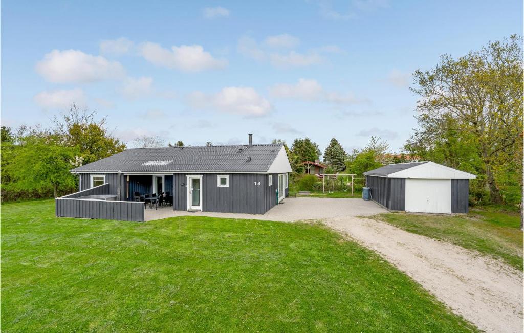 una casa gris con un garaje en un campo de césped en Cozy Home In Fars With Wifi en Hvalpsund