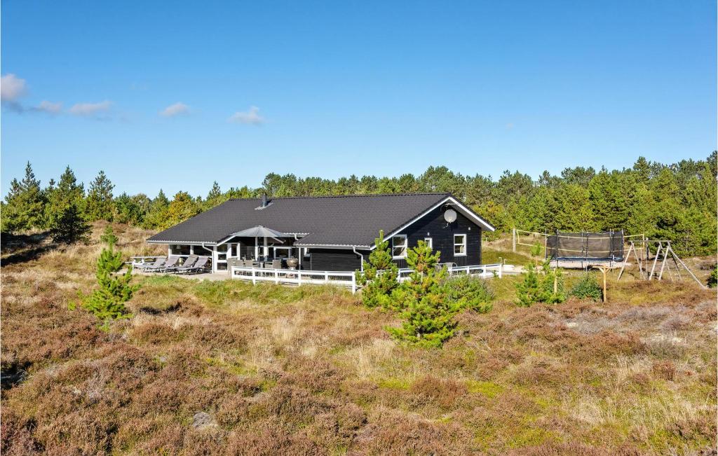 uma casa negra numa colina com árvores em 4 Bedroom Lovely Home In Rm em Rømø Kirkeby