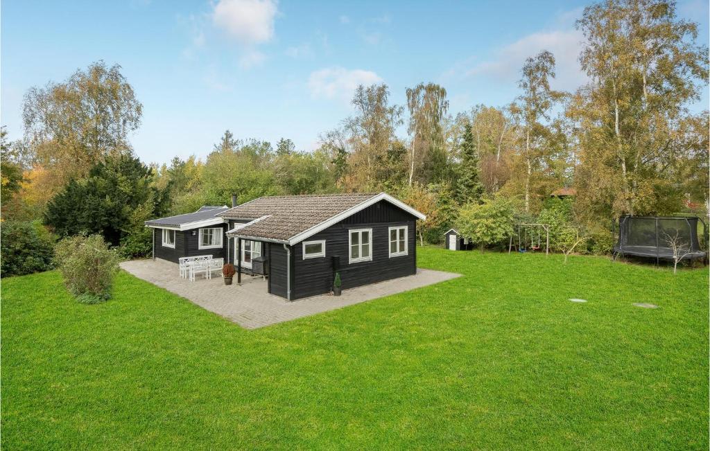 una pequeña cabaña negra en un campo de hierba en Beautiful Home In Askeby With Kitchen en Askeby