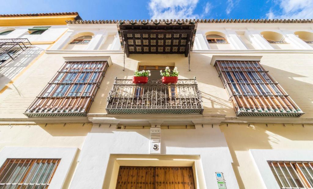 a building with two potted plants on a balcony at La Casa del Conde de Gelves Apartments in Seville