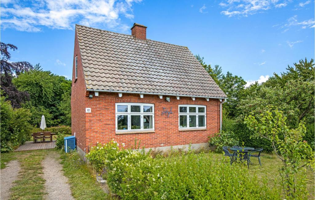 een klein rood bakstenen huis met een tafel en een bank bij Lovely Home In Rnne With Wifi in Rønne