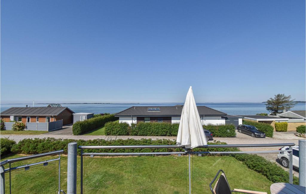 Nice Home In Assens With House Sea View في أسّينس: وجود مظلة بيضاء تجلس على العشب امام البيوت