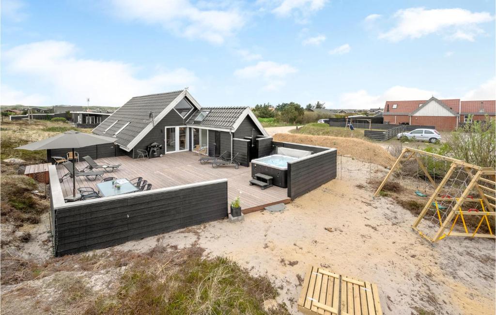 una piccola casa con terrazza e vasca idromassaggio di Three-Bedroom Holiday Home In Hvide Sande a Bjerregård