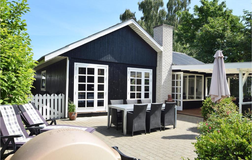 ヒュールスミンネにあるBeautiful Home In Juelsminde With 3 Bedrooms And Wifiの黒い家(テーブル、椅子、傘付)