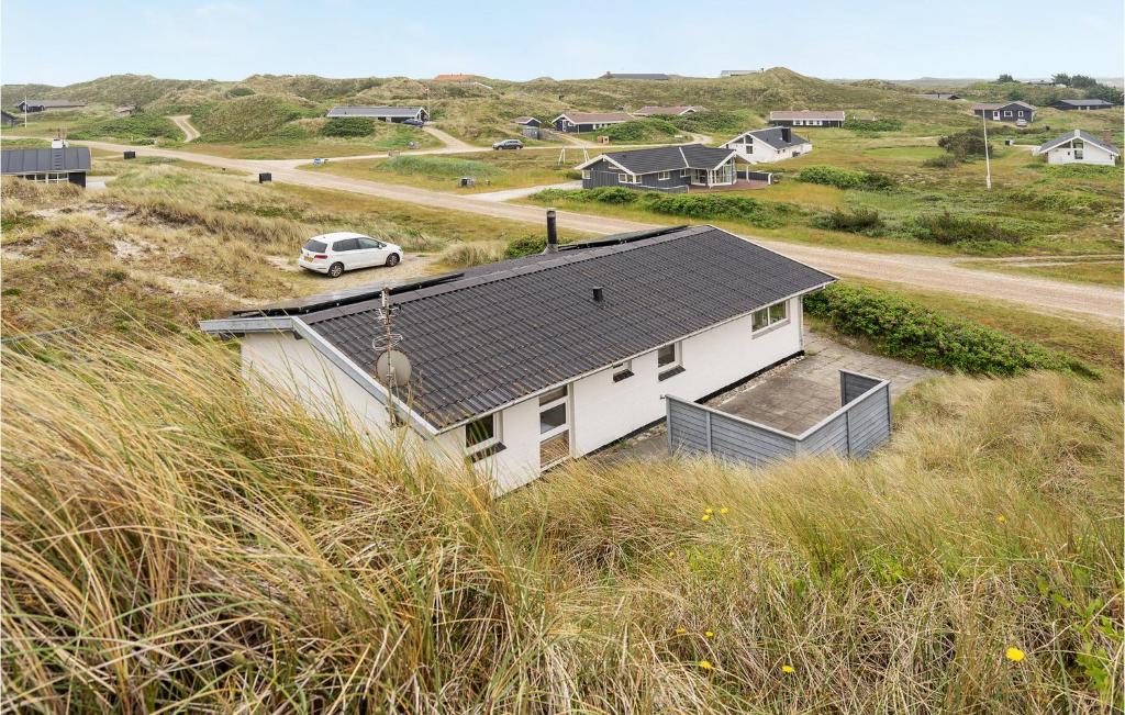 a white house in the middle of a field of grass at Stunning Home In Hvide Sande With 3 Bedrooms And Wifi in Havrvig