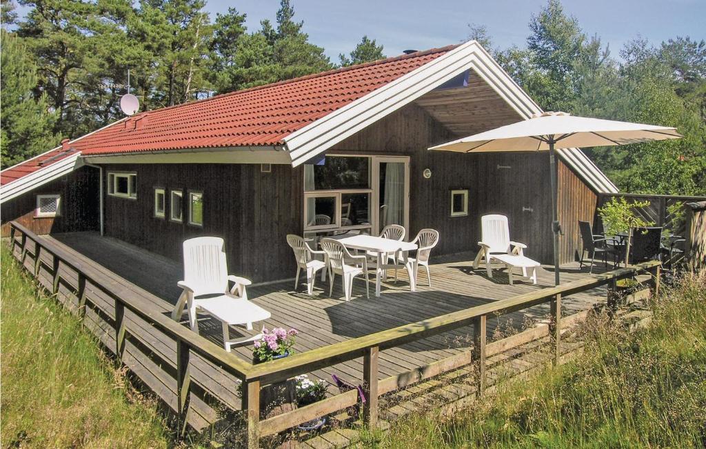 SnogebækにあるAmazing Home In Nex With 3 Bedrooms, Sauna And Wifiの木製デッキ(テーブル、椅子、パラソル付)