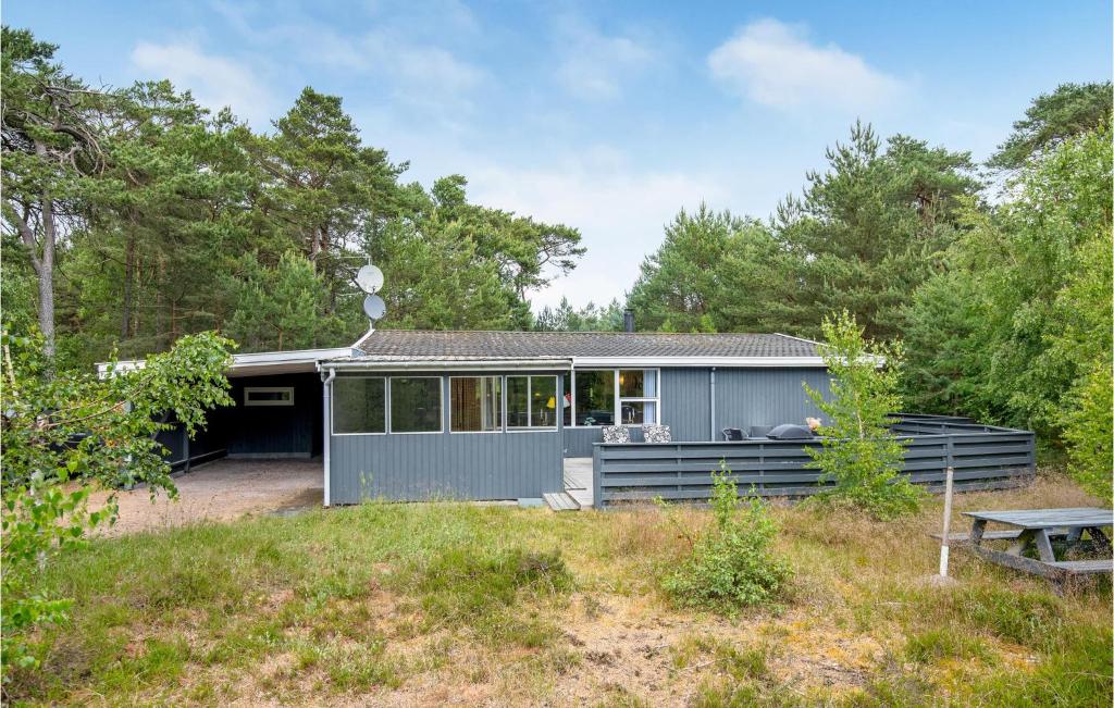 una casa gris en el bosque con una mesa de picnic en Jgerstuen, en Bedegård