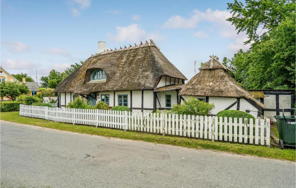 une vieille maison avec une clôture blanche dans l'établissement 3 Bedroom Stunning Home In Rudkbing, à Illebølle