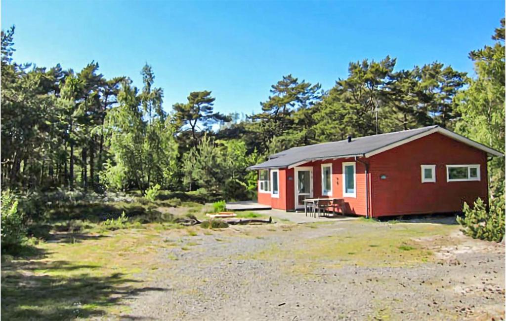 a red cabin in the middle of a forest at 3 Bedroom Nice Home In Aakirkeby in Vester Sømarken