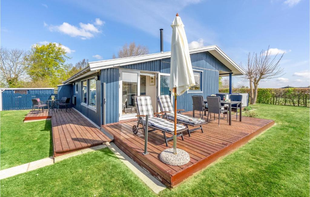 una casa azul con terraza y sombrilla en Gorgeous Home In Karrebksminde With Kitchen, en Karrebæksminde