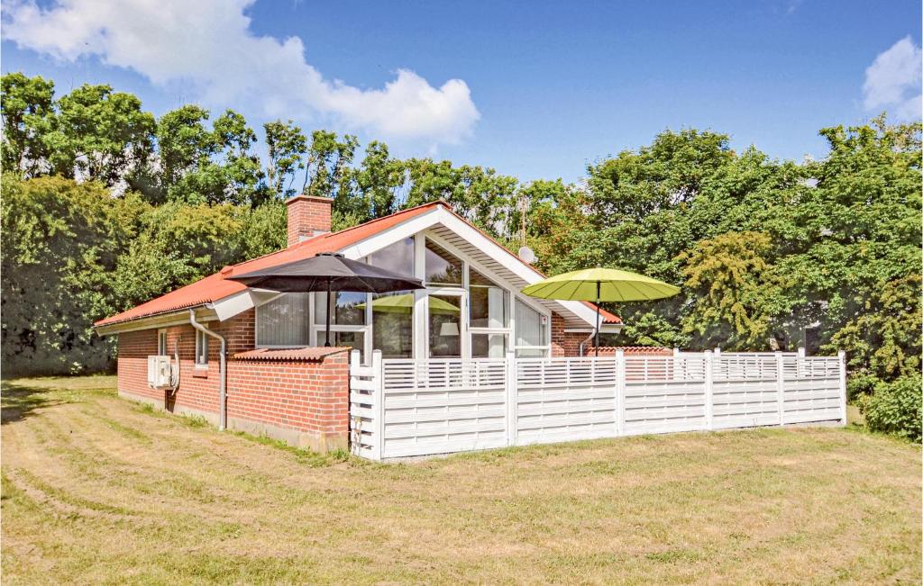 a small house with a white fence and two umbrellas at Holiday Home Gunhildsvej Vestervig Vi in Vestervig