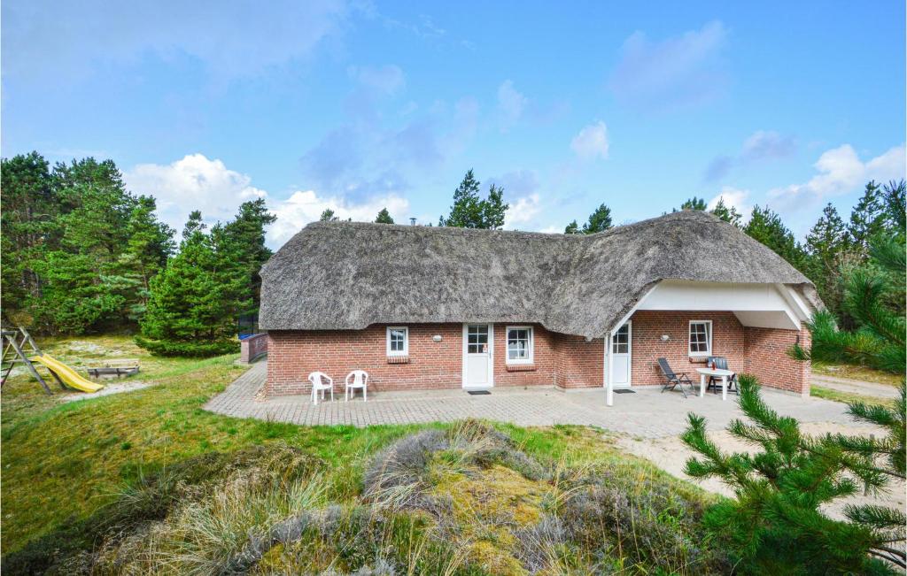 uma casa com telhado de palha e um parque infantil em Amazing Home In Rm With Sauna em Rømø Kirkeby