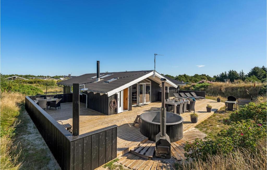 una casa en una terraza con una hoguera en Cozy Home In Hvide Sande With Sauna, en Bjerregård
