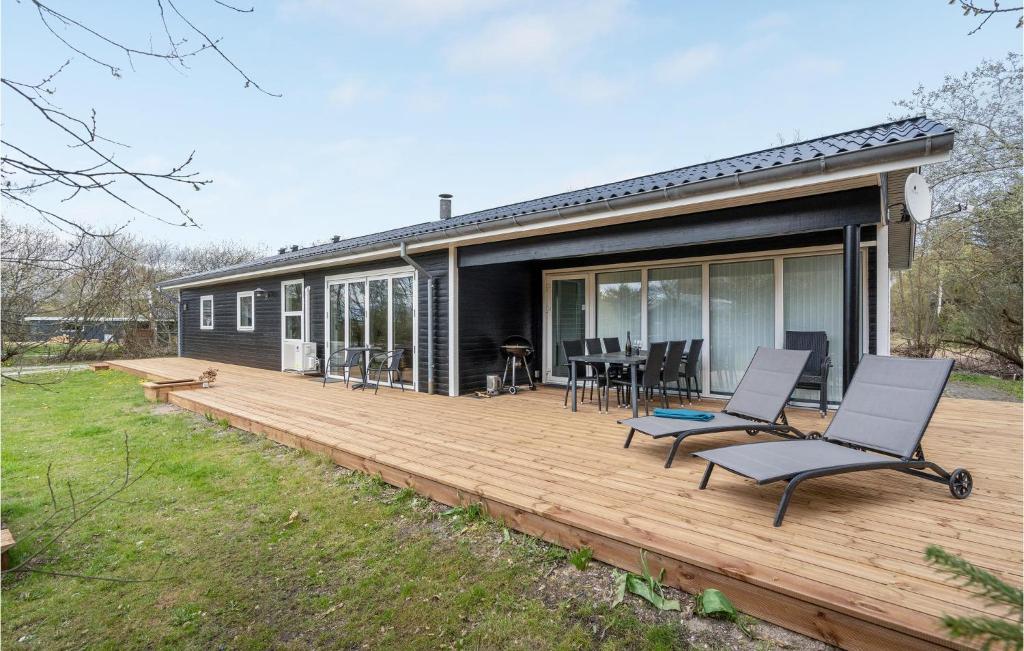 エーベルトフトにあるBeautiful Home In Ebeltoft With 4 Bedrooms, Wifi And Indoor Swimming Poolの木製デッキ(椅子付)が備わる家