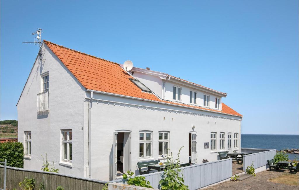 a white house with an orange roof next to the ocean at Awesome Apartment In Allinge With 2 Bedrooms And Wifi in Allinge