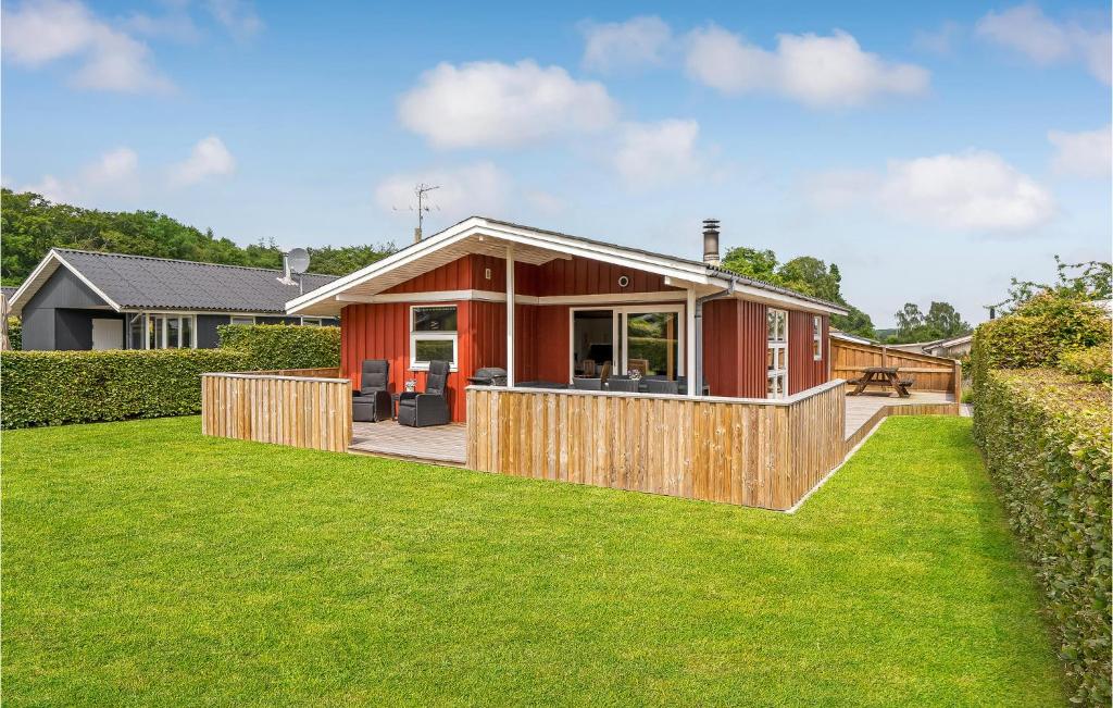 Gorgeous Home In Bjert With Kitchen في Sønder Bjert: منزل أحمر صغير مع حديقة خضراء