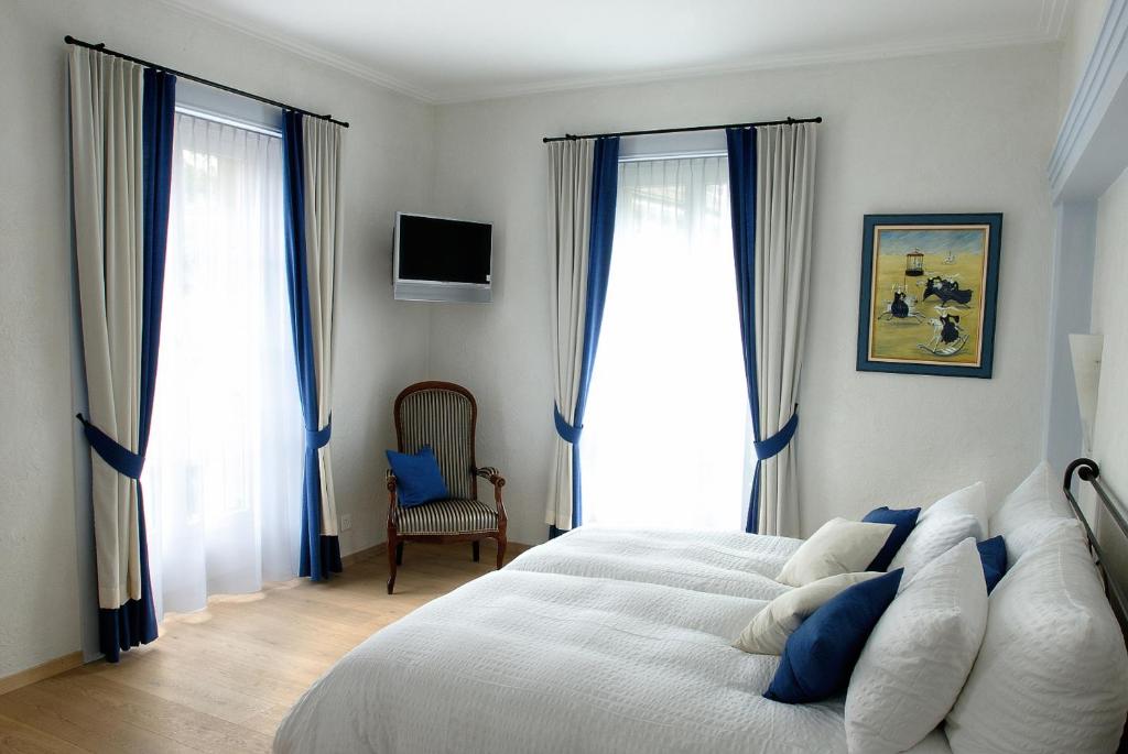 a bedroom with a bed and two large windows at Romantik Hotel Landhaus Liebefeld in Bern