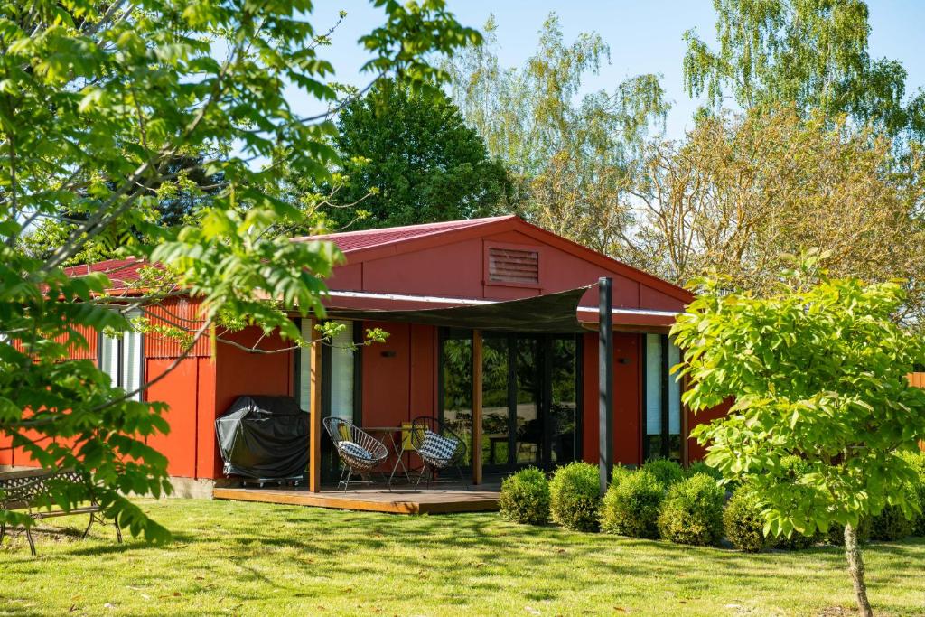 a red house with two chairs in a yard at River Road Retreat in Nelson