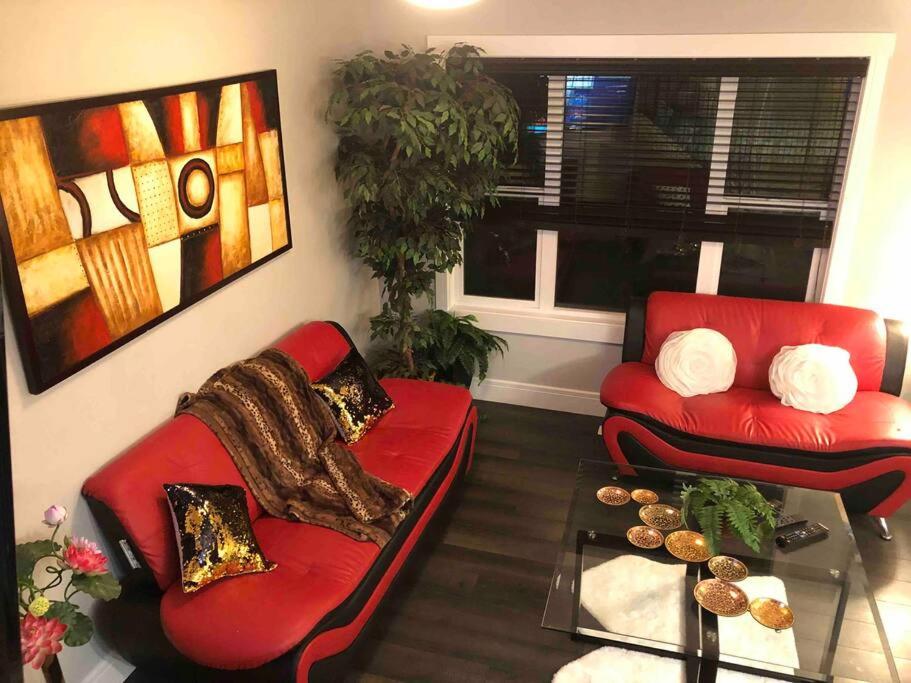 ein Wohnzimmer mit zwei roten Sofas und einem Tisch in der Unterkunft Cheerful and beautiful 3 bedroom home close lake in Edmonton