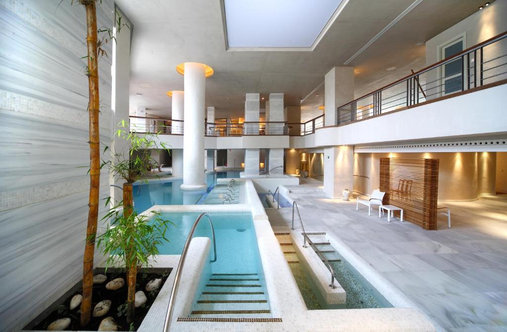 an indoor pool in a building with stairs and tables at Royal Hideaway Sancti Petri in Chiclana de la Frontera