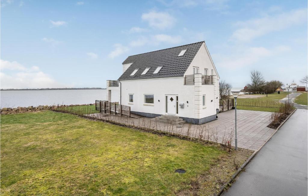 una casa blanca con un techo negro junto al agua en 5 Bedroom Amazing Home In Torrig L, en Kragenæs