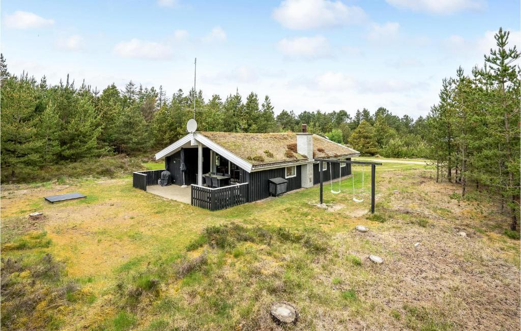 a black house with a grass roof on a field at Cozy Home In Rm With Kitchen in Bolilmark