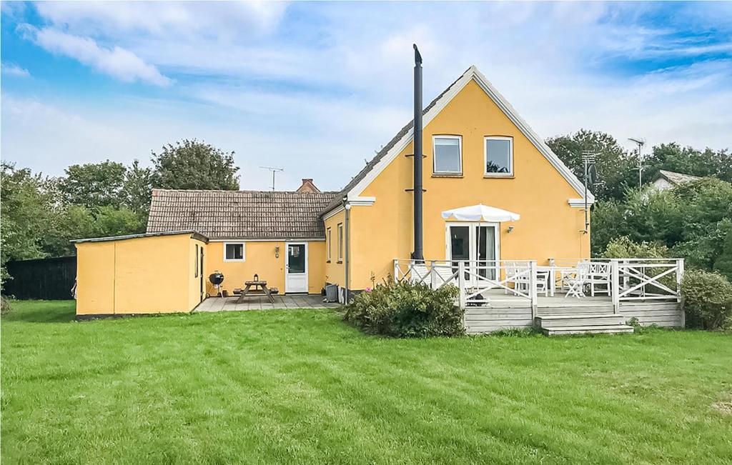 a yellow house with a large yard in front of it at Cozy Home In stermarie With Kitchen in Østermarie