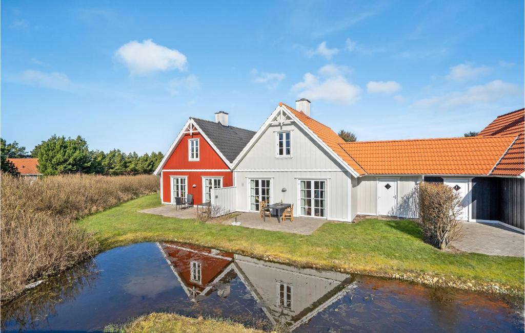 een rood-wit huis met een reflectie in het water bij Blvandslyst in Blåvand