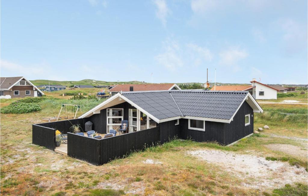 a black house with a solar roof on a beach at 3 Bedroom Stunning Home In Hvide Sande in Bjerregård