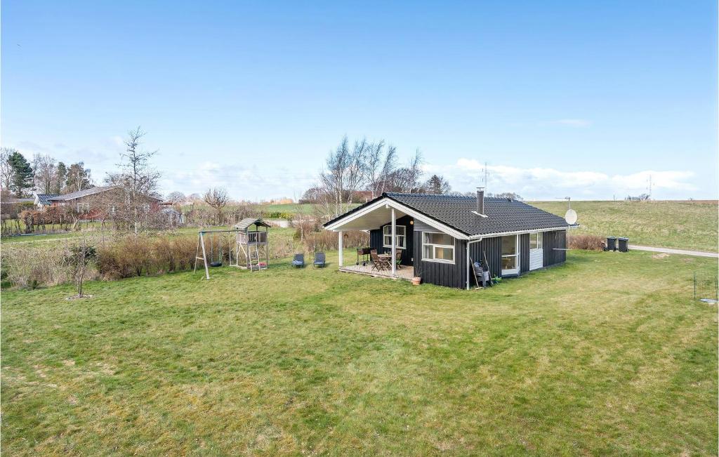 a small house in a field with a yard at Awesome Home In Askeby With 4 Bedrooms, Sauna And Wifi in Askeby