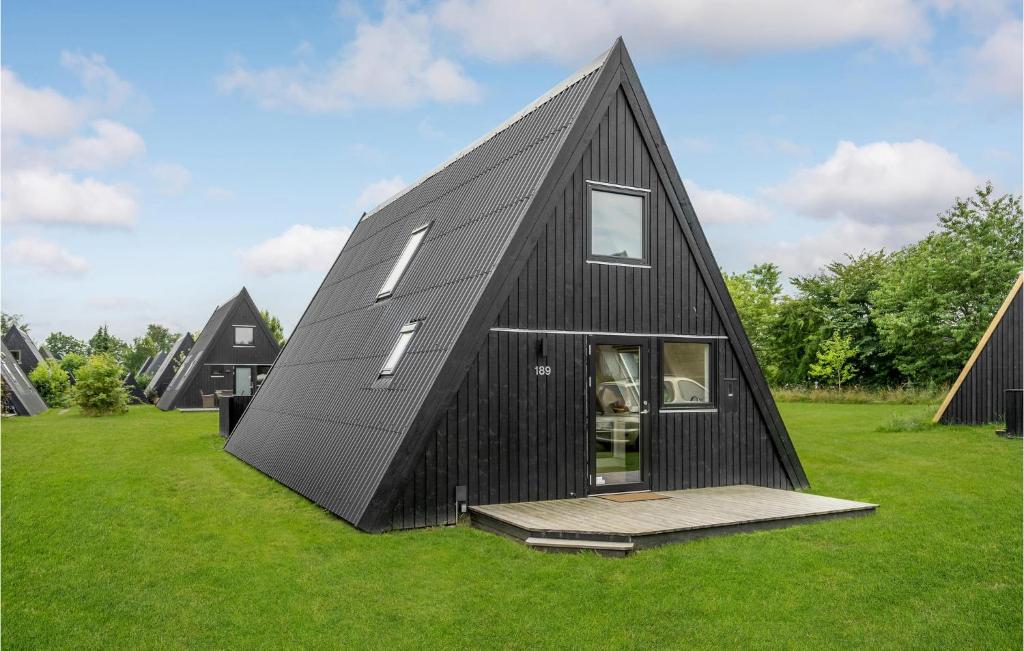une maison recouverte de noir dans un champ d'herbe dans l'établissement Nice Home In Fars With Wifi And 2 Bedrooms, à Farsø