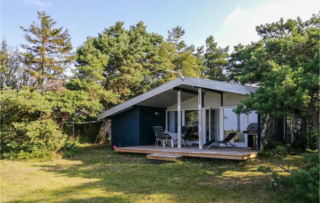 Skødshoved StrandにあるAwesome Home In Knebel With 3 Bedrooms And Wifiの小さな青いコテージ(芝生のデッキ付)