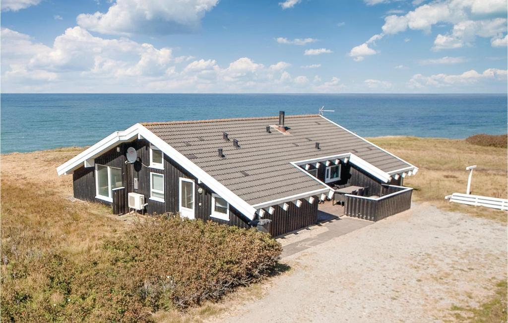 a house on the beach with the ocean behind it at Cozy Home In Hjrring With House Sea View in Lønstrup