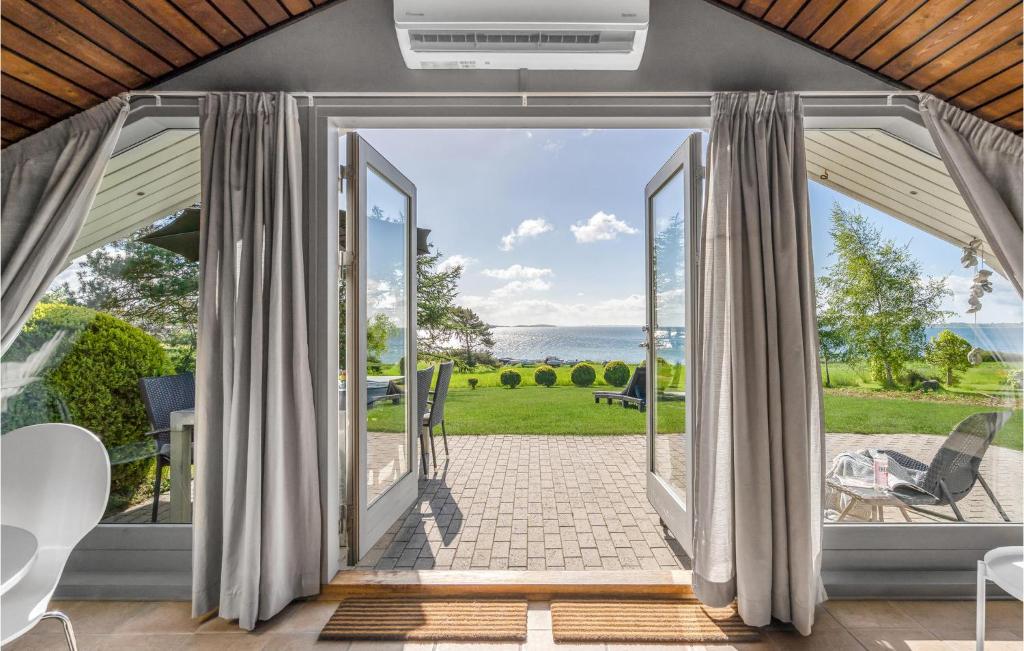 ファーボにあるGorgeous Home In Faaborg With Wifiの海の景色を望むパティオへ続くオープンドア