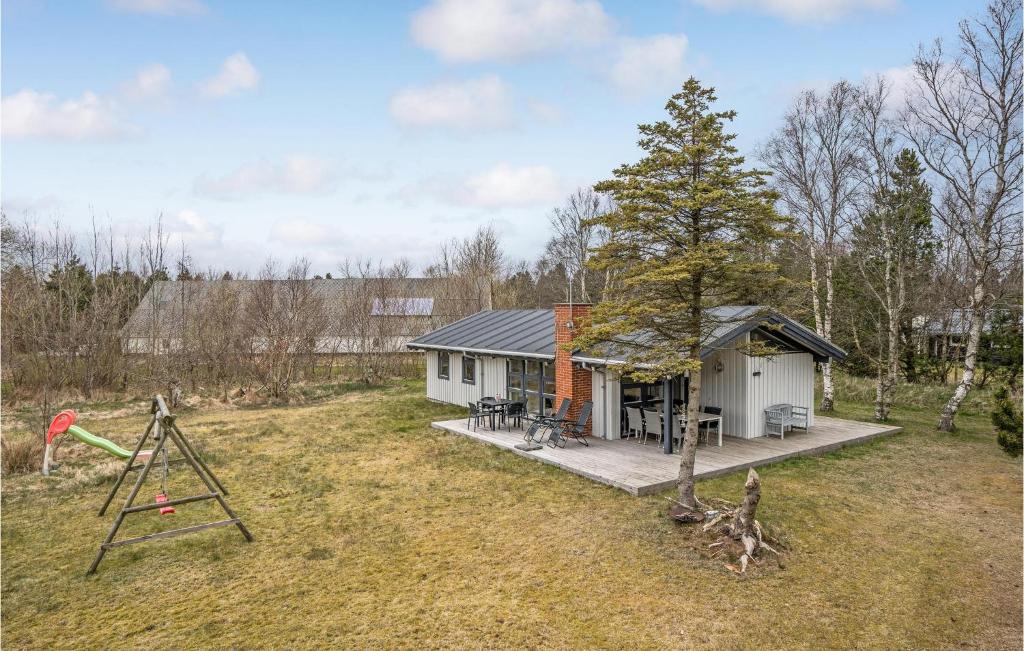 una pequeña casa con un parque infantil en un campo en Gorgeous Home In Strandby With Kitchen, en Strandby