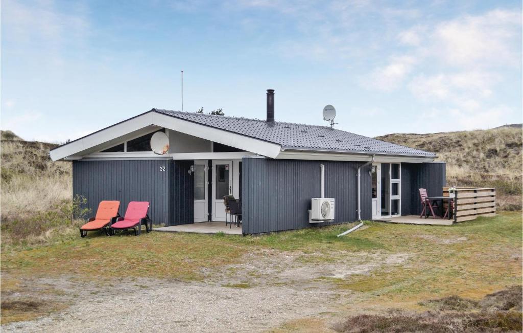 a gray house with two red chairs in front of it at 3 Bedroom Beautiful Home In Hvide Sande in Havrvig