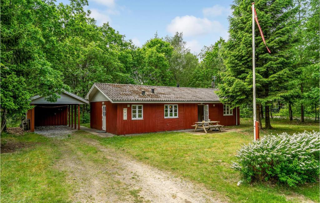a red cabin in the woods with a dirt road at Pet Friendly Home In Ansager With Kitchen in Ansager
