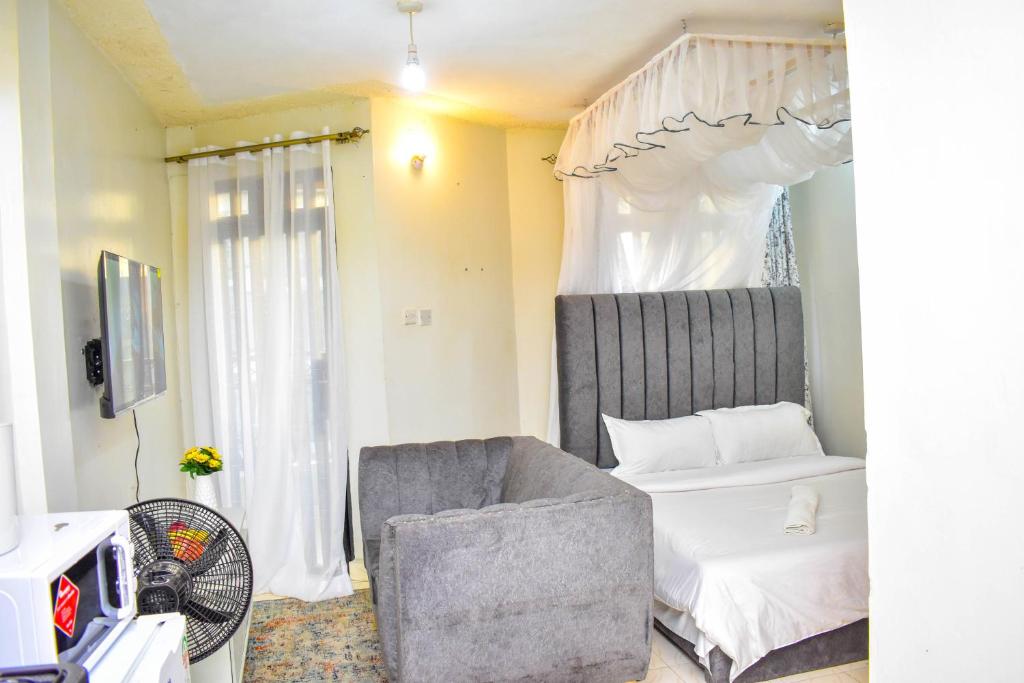 a bedroom with a bed and a chair and a tv at Unique, Stylish Studio Apartment in Kisumu