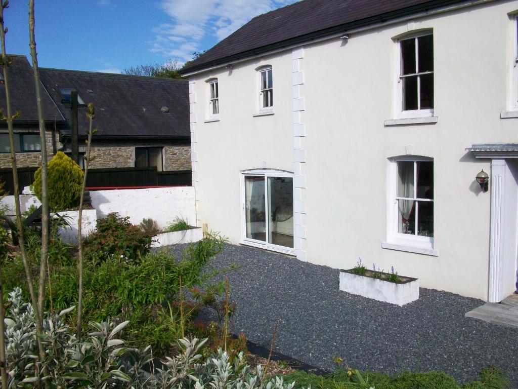 a white house with a garden in front of it at Bryncoch in Llannon