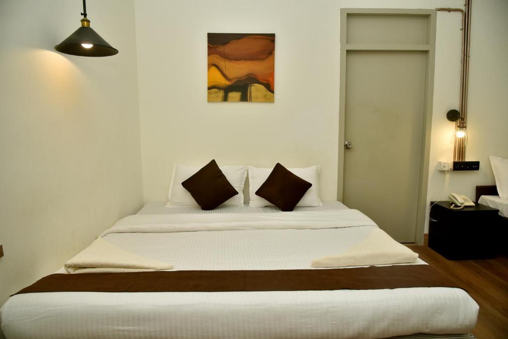 a bedroom with a large white bed with brown pillows at Convastay Royapettah in Chennai