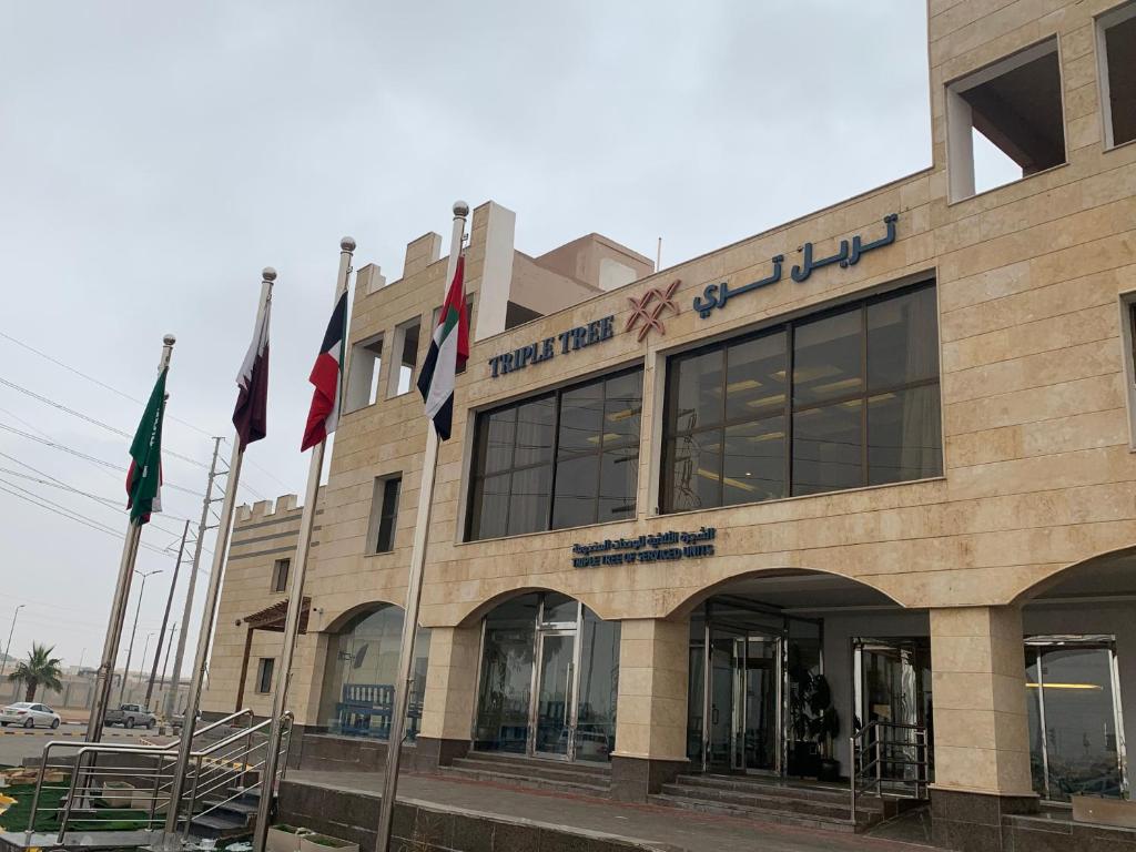 um edifício com bandeiras à sua frente em Triple Tree em Al-Hofuf